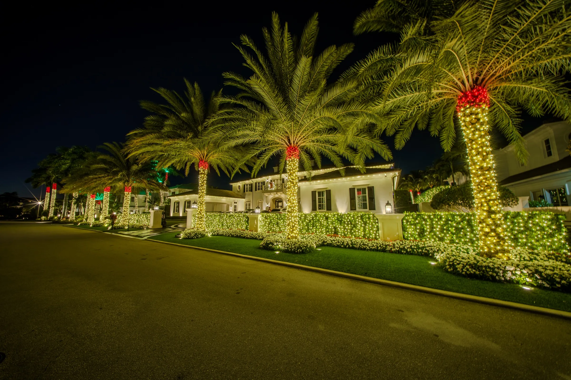 Wide cinematic view of an upscale estate at night with restrained warm-white holiday lighting